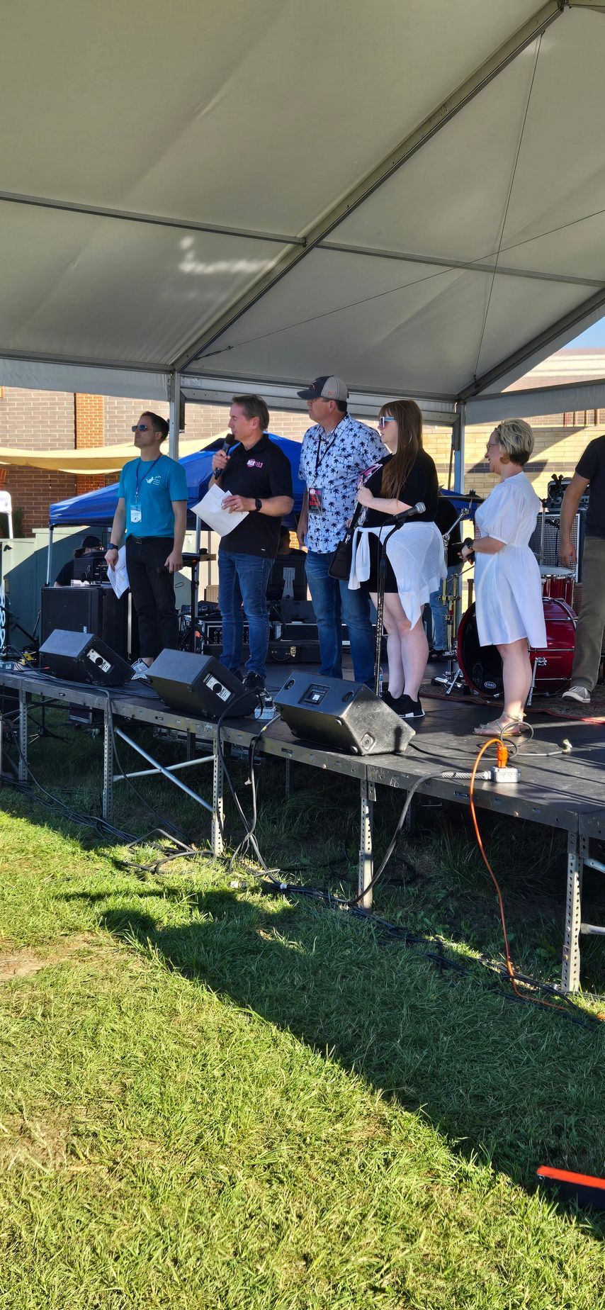 A group of people are standing on a stage under a tent.