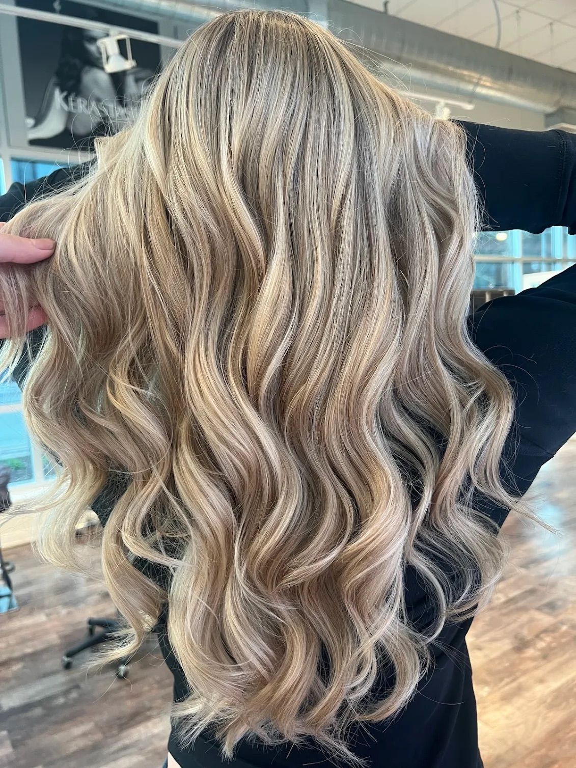 Long wavy blonde hair styled with highlights.