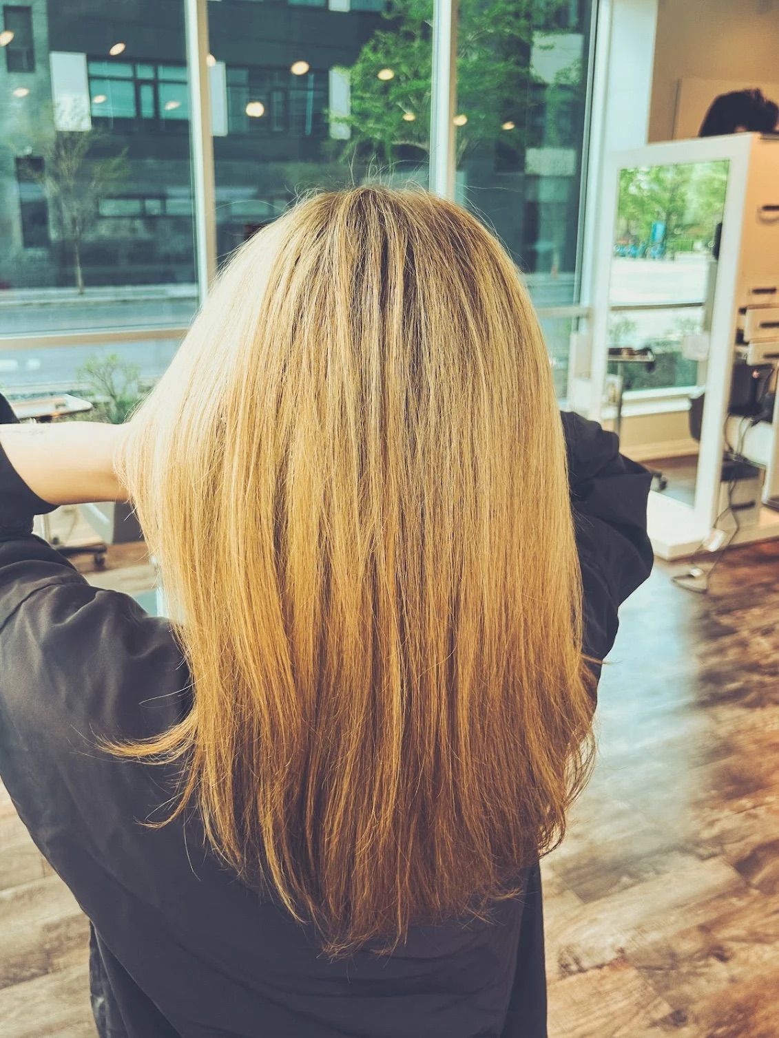 Blonde woman with wavy hair smiling, after hair coloring appointment, eyes closed.