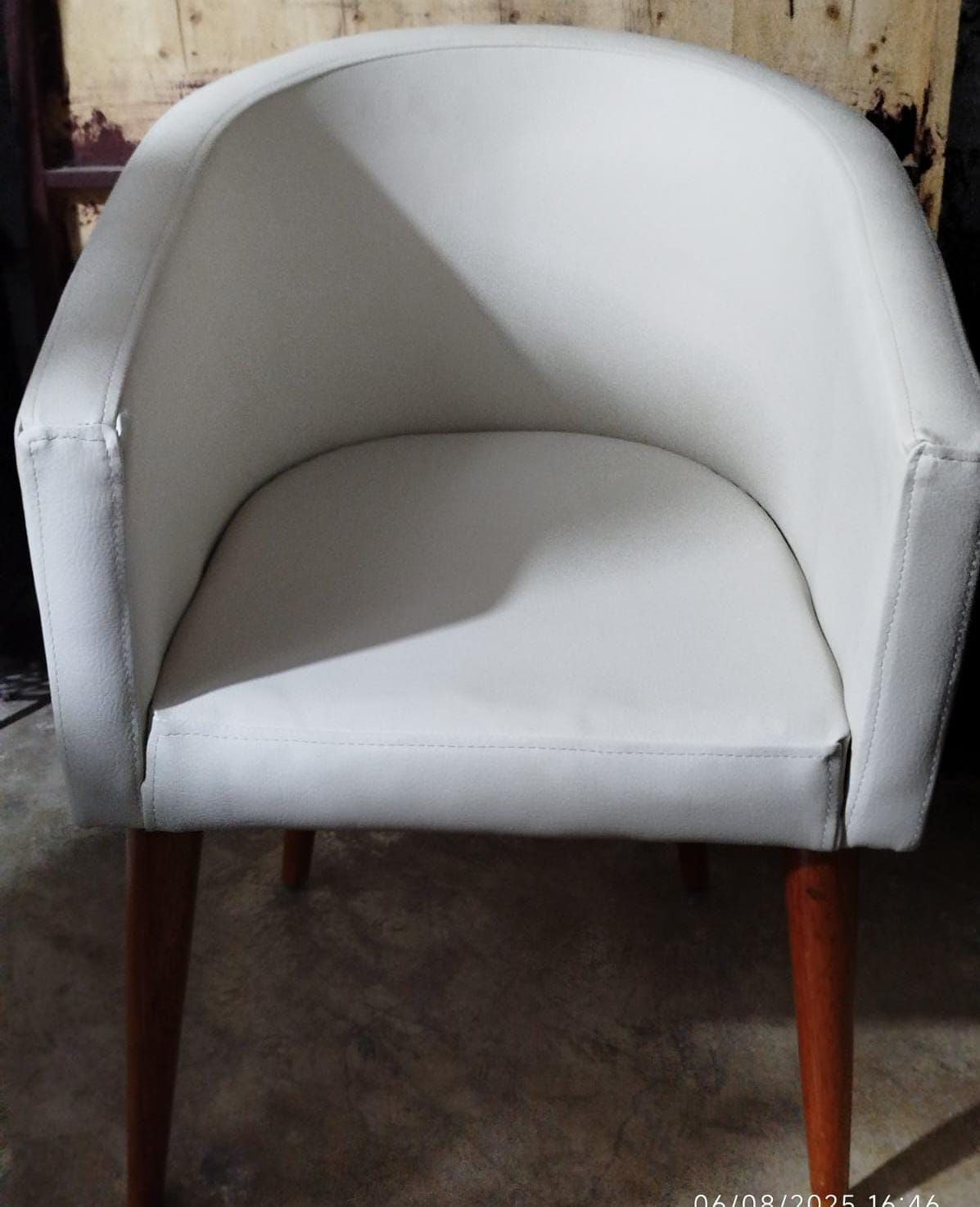 Sillón tapizado en color blanco con respaldo curvado y patas de madera.