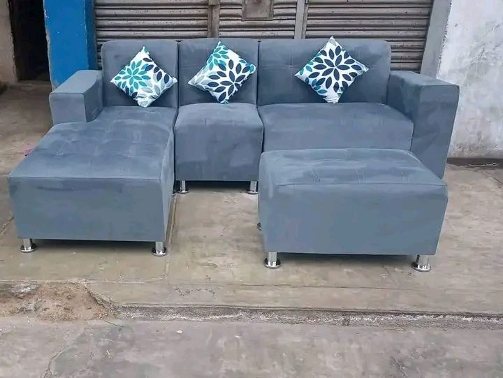 Sofá seccional gris con otomana y tres almohadas decorativas.