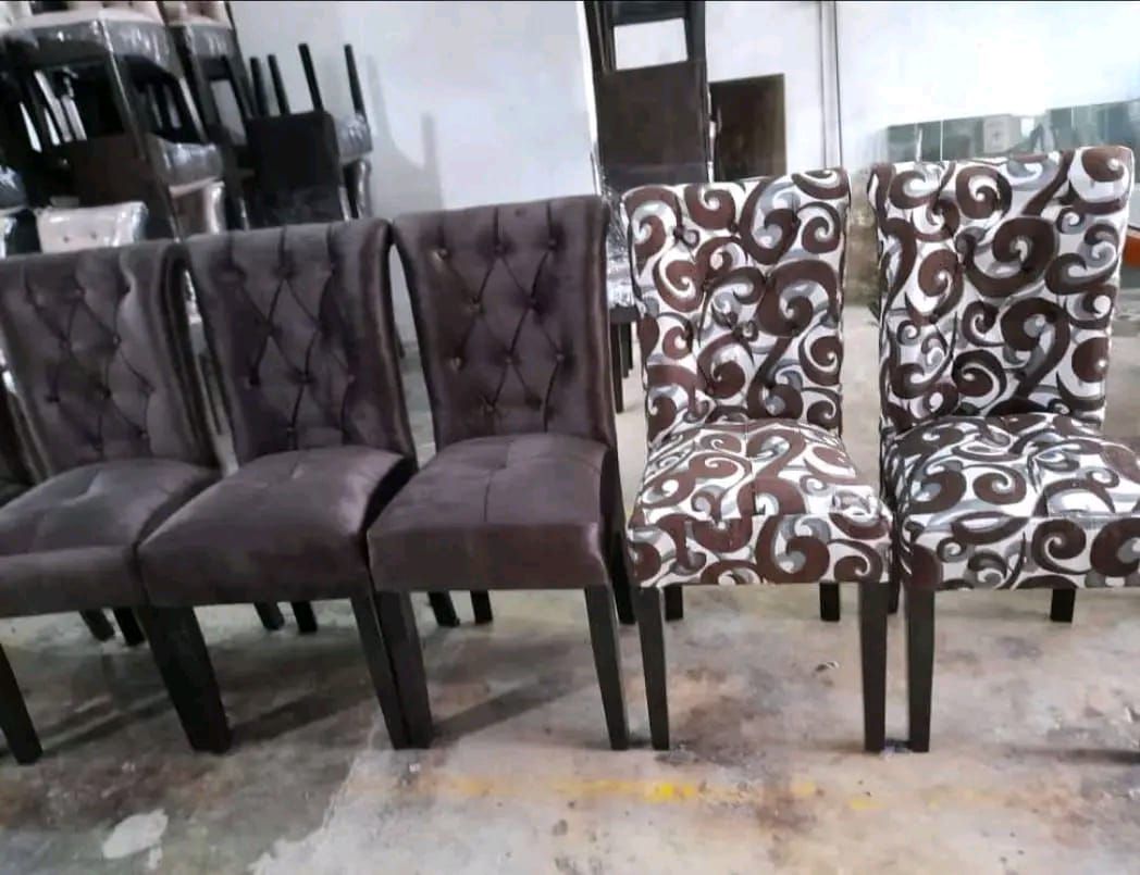 Cuatro sillas de comedor: dos de color marrón liso y dos estampadas, con patas oscuras, en un entorno de almacén.
