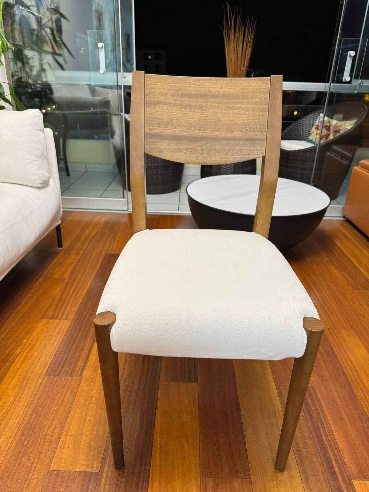 Silla de madera con cojín blanco y respaldo tejido, colocada sobre un suelo de madera.