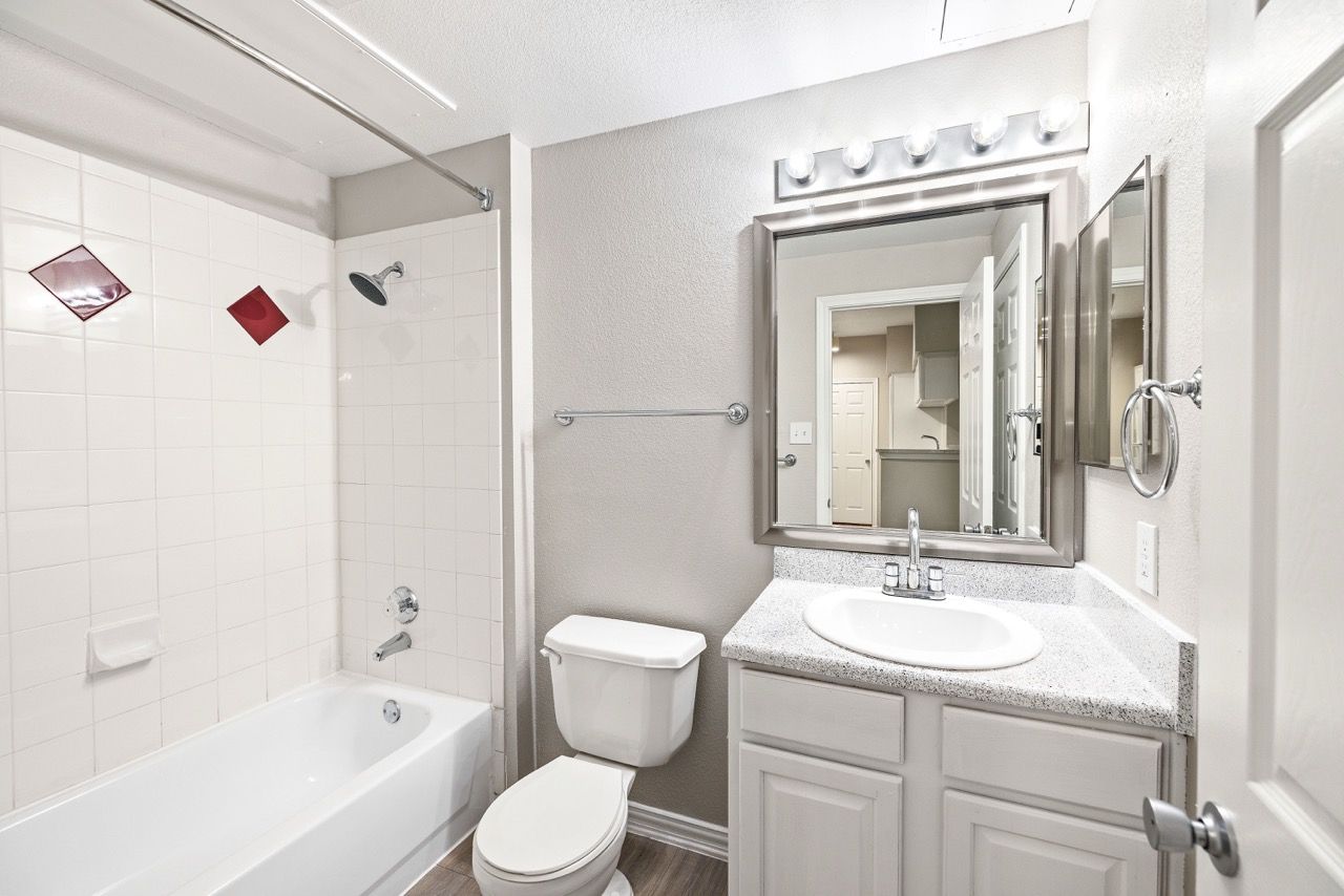 Bathroom with vanity, mirror, toilet, and bathtub/shower.