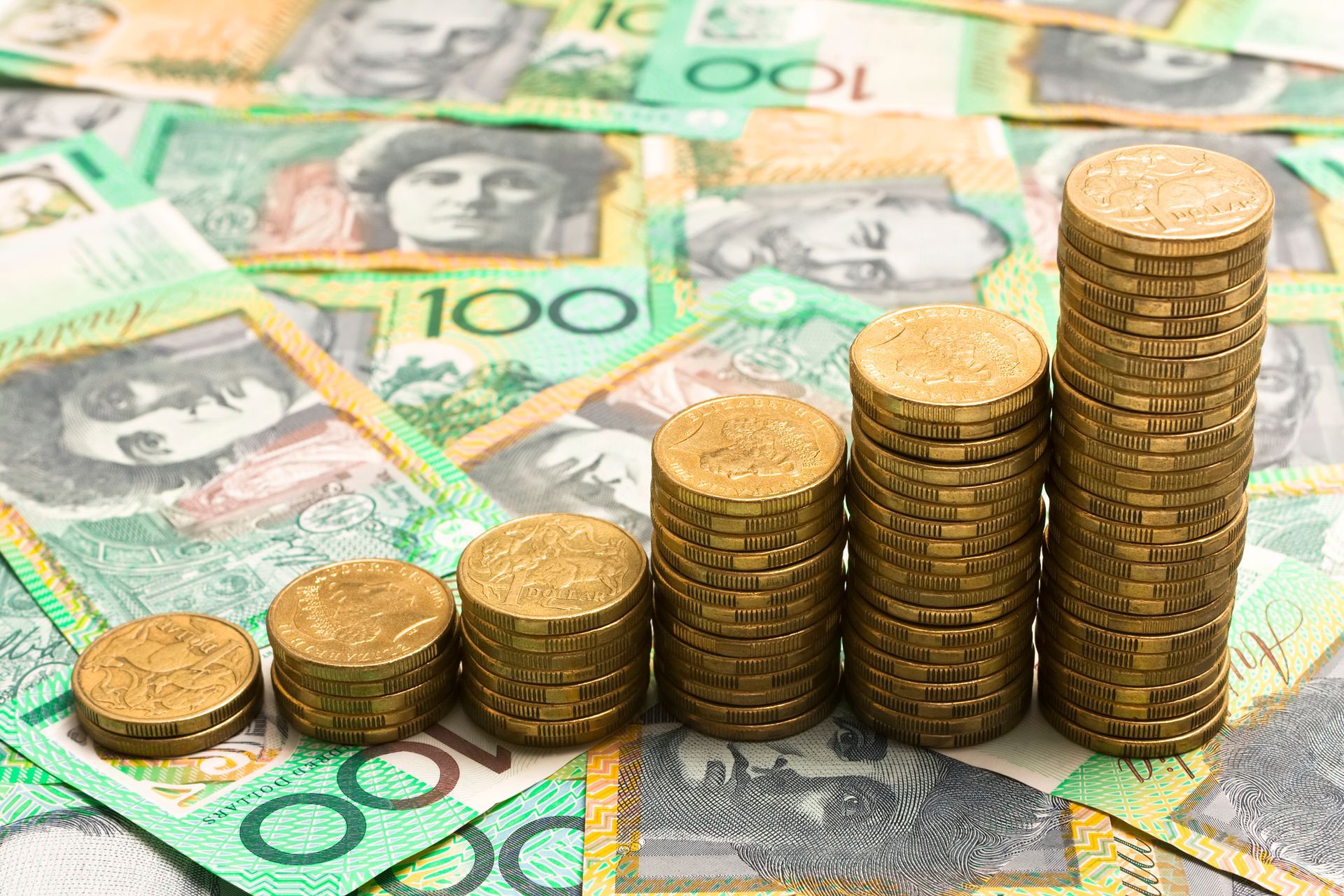 A stack of gold coins sitting on top of a pile of money.