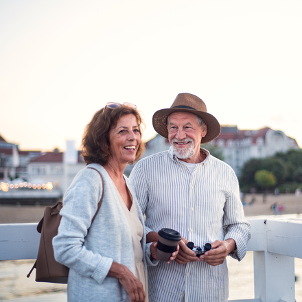 A man and a woman are standing next to each other on a bridge overlooking a body of water.