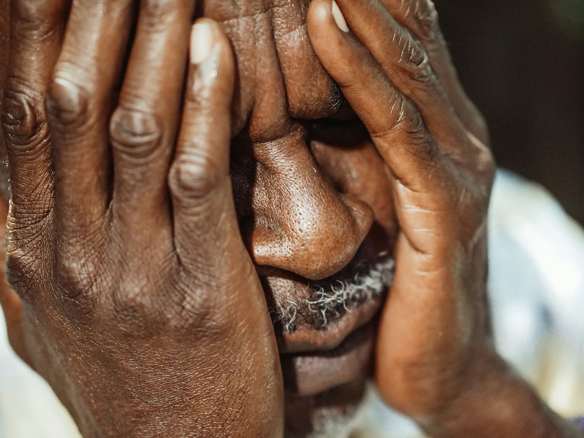 Man with hands covering his face, appearing distressed.