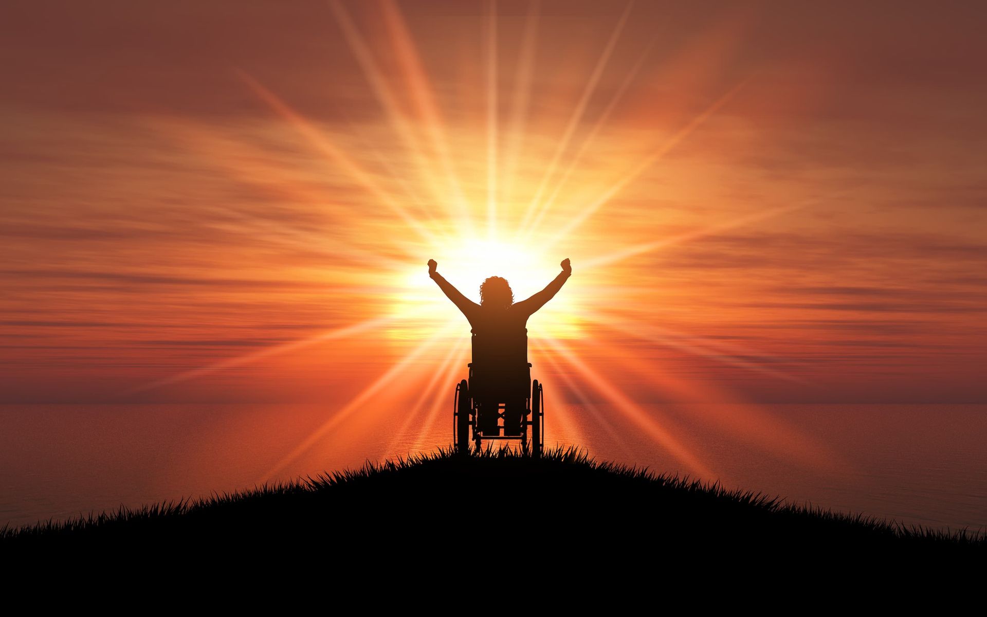 A person in a wheelchair with their arms outstretched in front of the sun at sunset.