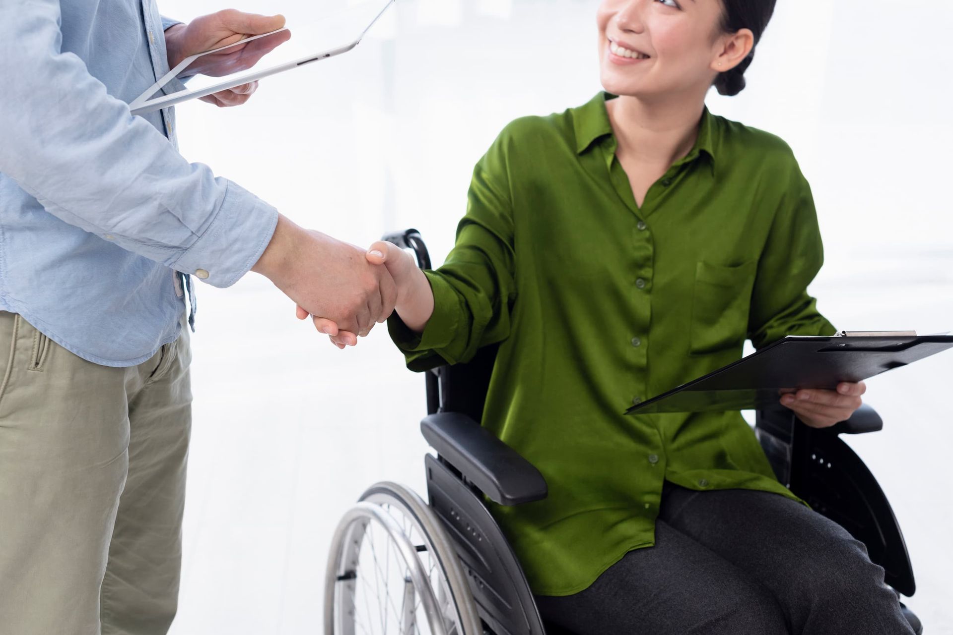A woman in a wheelchair is shaking hands with a man.