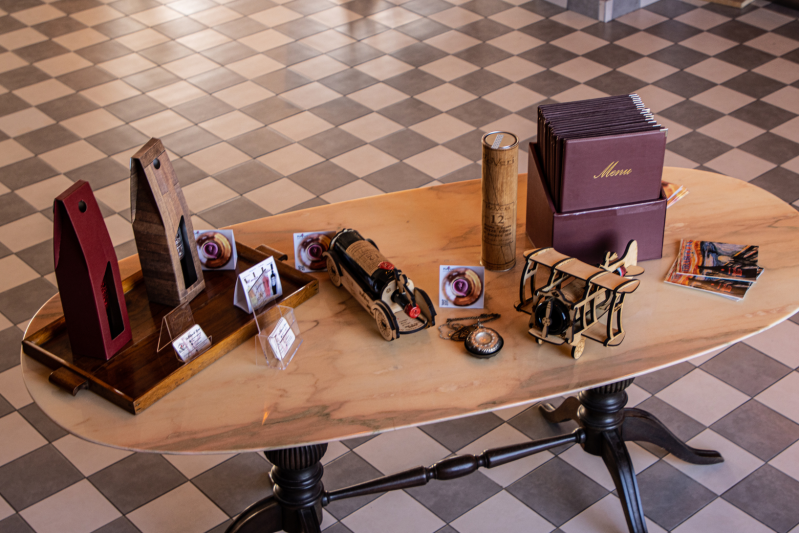 Vari articoli da regalo, tra cui scatole, un'auto di legno e sculture, disposti su un tavolo di legno.