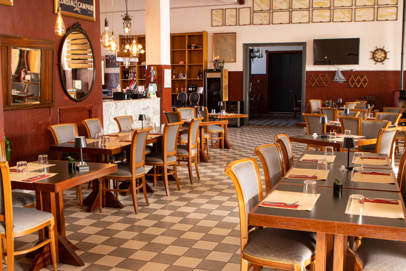 Sala da pranzo del ristorante con tavoli, sedie, pavimento a scacchi e arredamento a tema nautico.