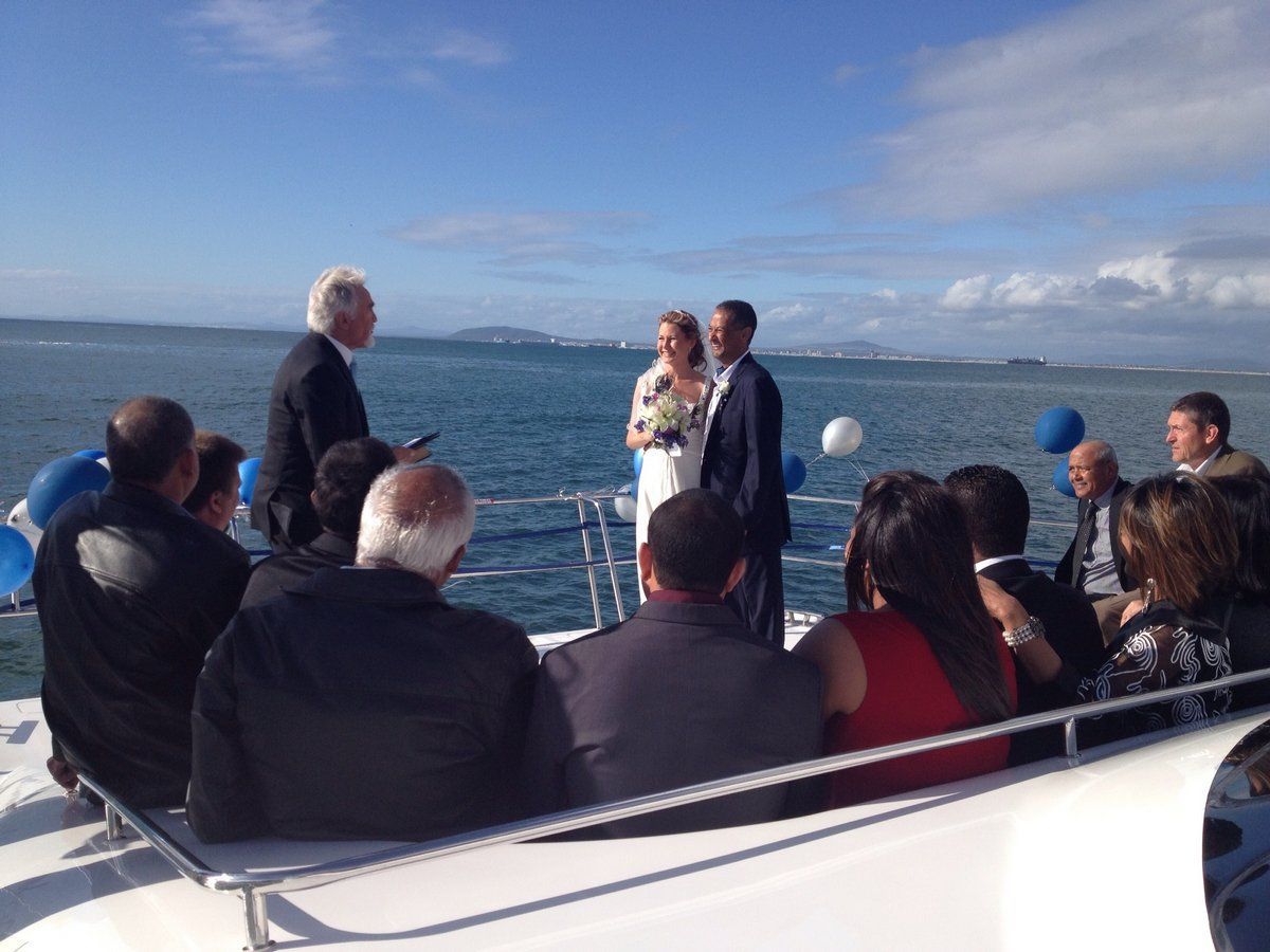 A bride and groom are getting married on a boat in the ocean.