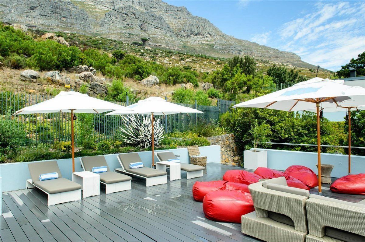 A deck with chairs and umbrellas with a mountain in the background