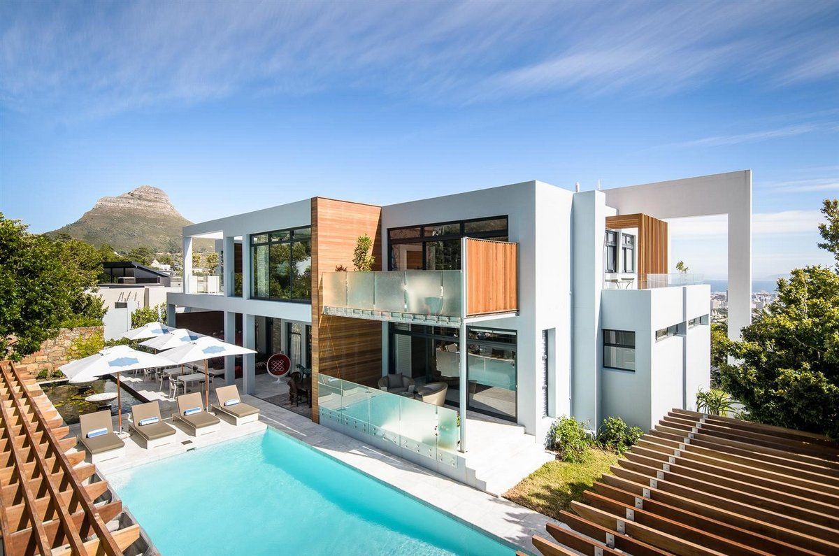 A large modern house with a swimming pool in front of it.