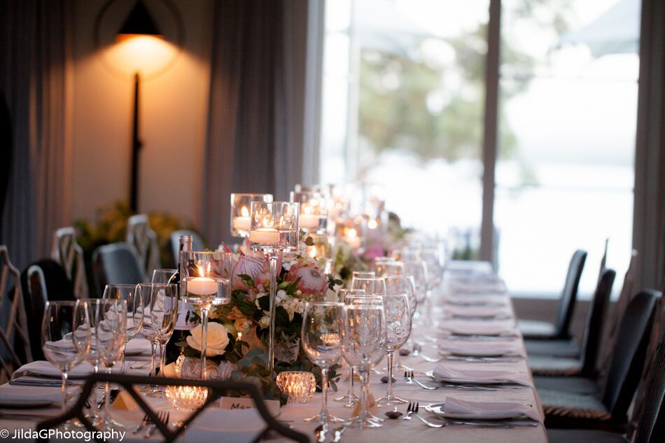 A long table with a vase of flowers and candles on it.