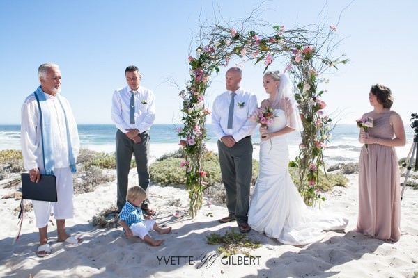 A bride and groom are getting married on the beach