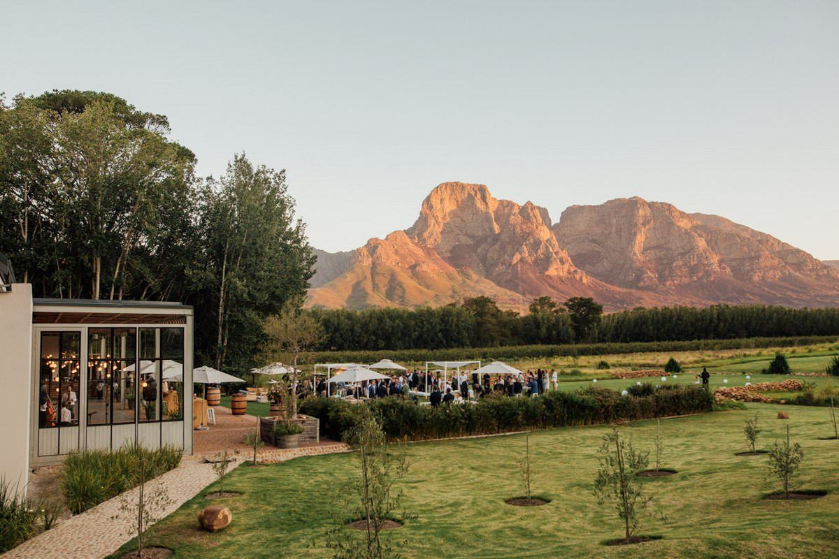A group of people are sitting in a field with a mountain in the background.