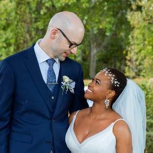 A man in a suit and tie is standing next to a woman in a wedding dress.