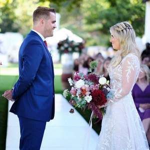 A bride and groom are standing next to each other holding a bouquet of flowers.