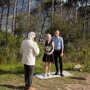 A man is taking a picture of a bride and groom during their wedding ceremony in the woods.