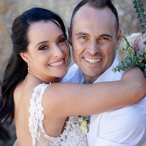 A bride and groom are hugging each other and smiling for the camera.