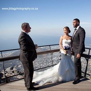 A bride and groom are standing next to each other on a balcony overlooking a city.