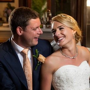 A bride and groom are sitting next to each other and smiling.
