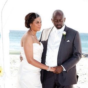 A bride and groom are posing for a picture on the beach.