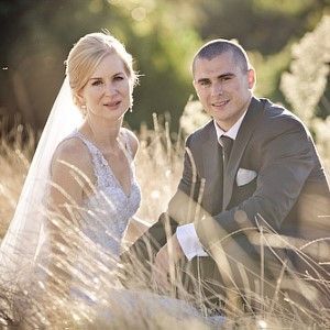 A bride and groom are sitting in a field of tall grass.