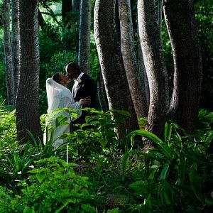 A bride and groom are kissing in the middle of a forest.