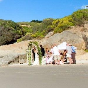 A bride and groom are getting married on the beach.