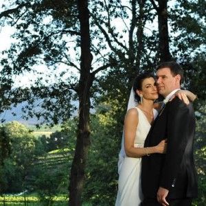 A bride and groom pose for a picture in front of trees