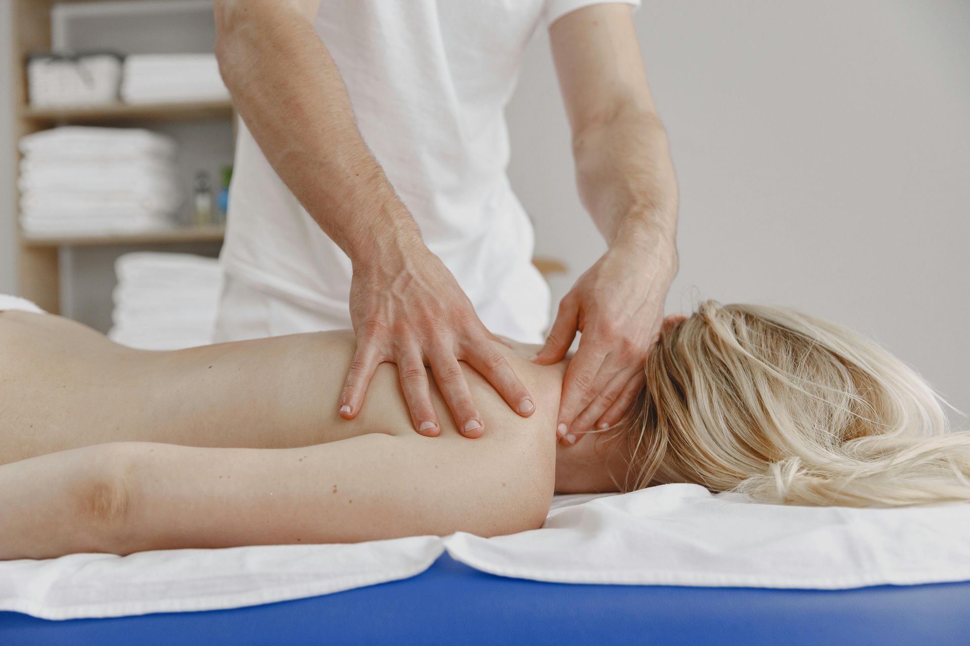 Een massagetherapeut voert een schouder- en nekmassage uit bij een cliënt.