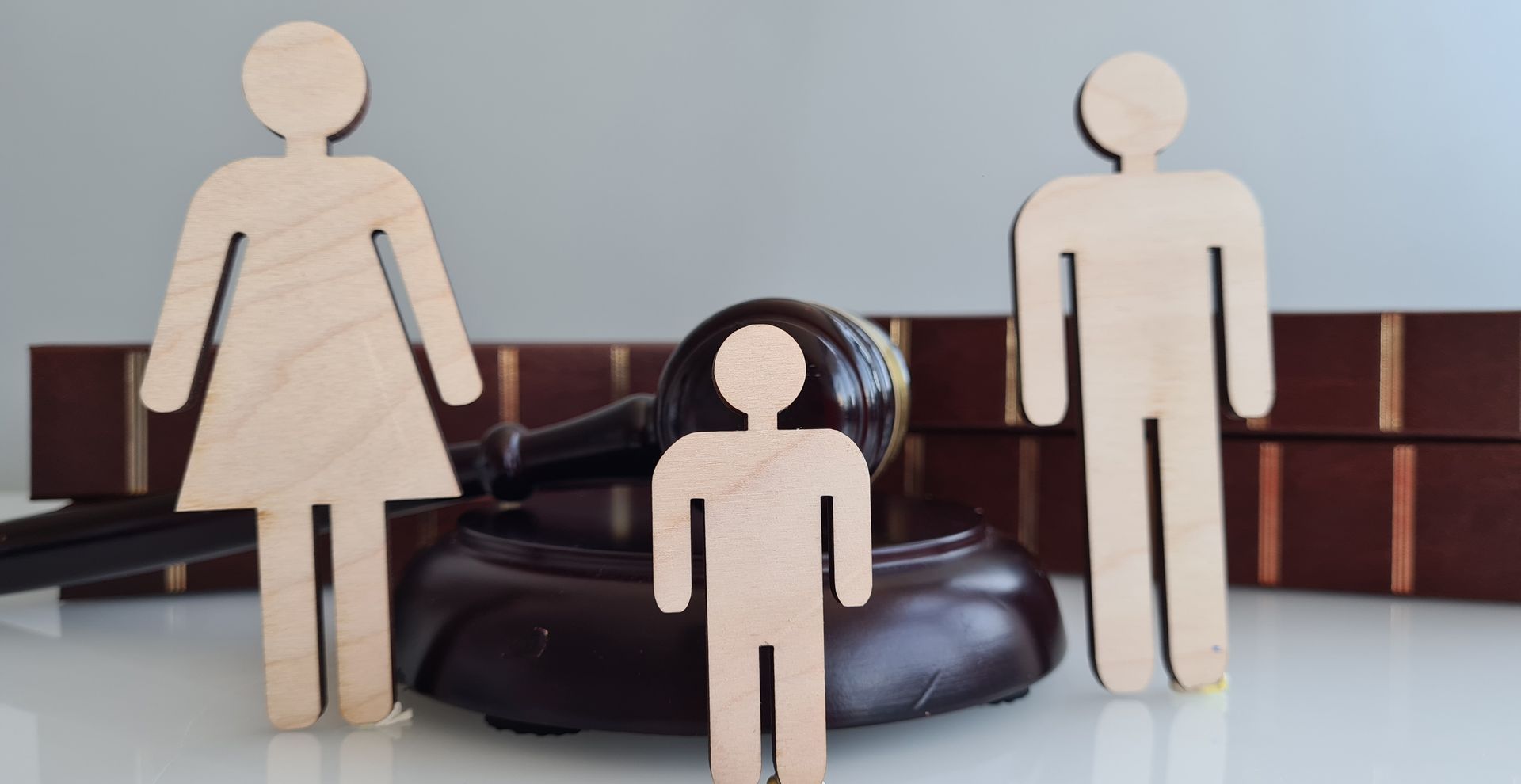 Wooden figures representing a family near a gavel and law books.