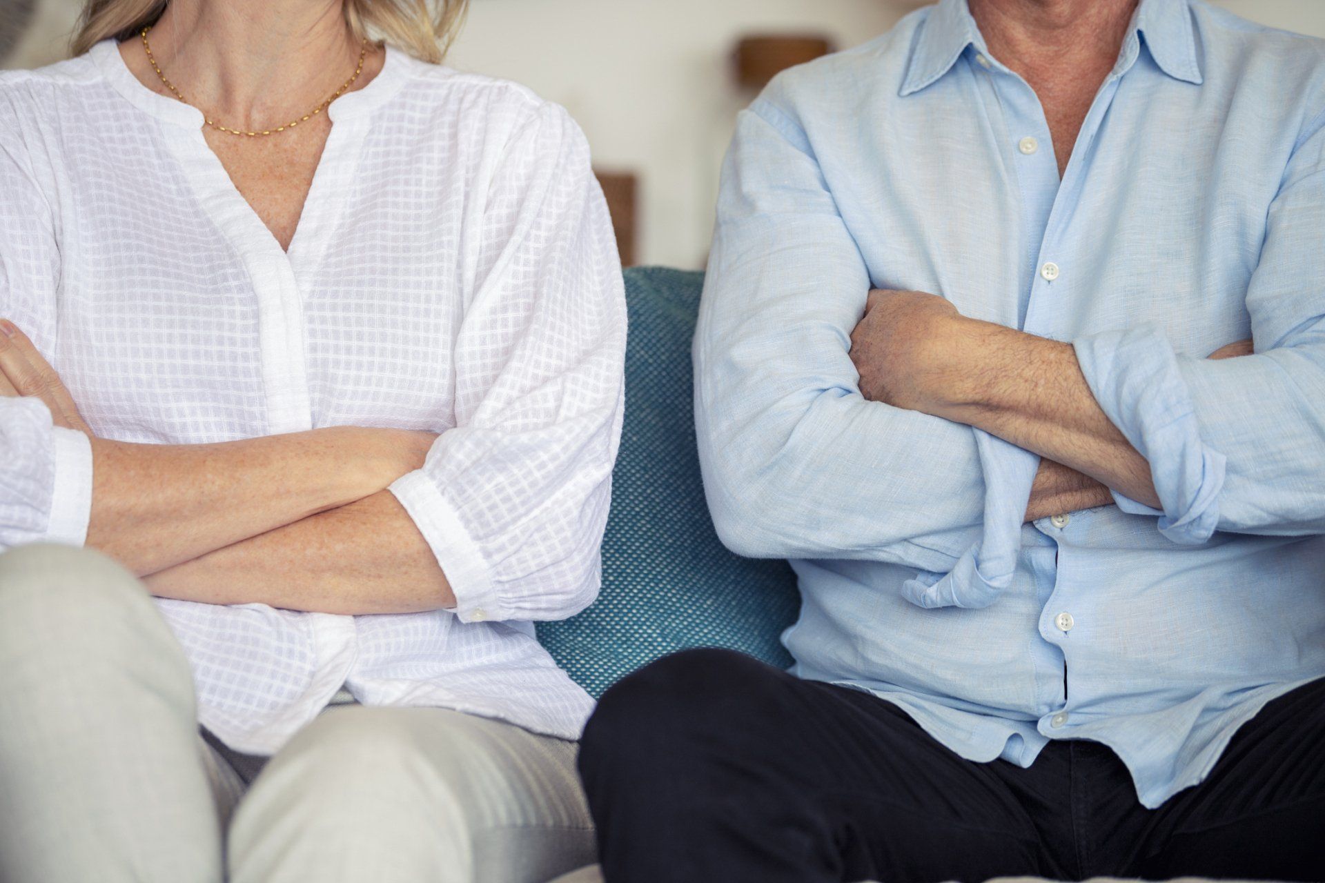 Couple seated close together, arms crossed, appear angry or in disagreement.