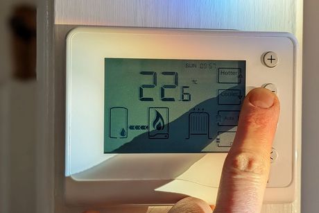 A person is pressing a button on a thermostat. A person is pressing a button on a thermostat.