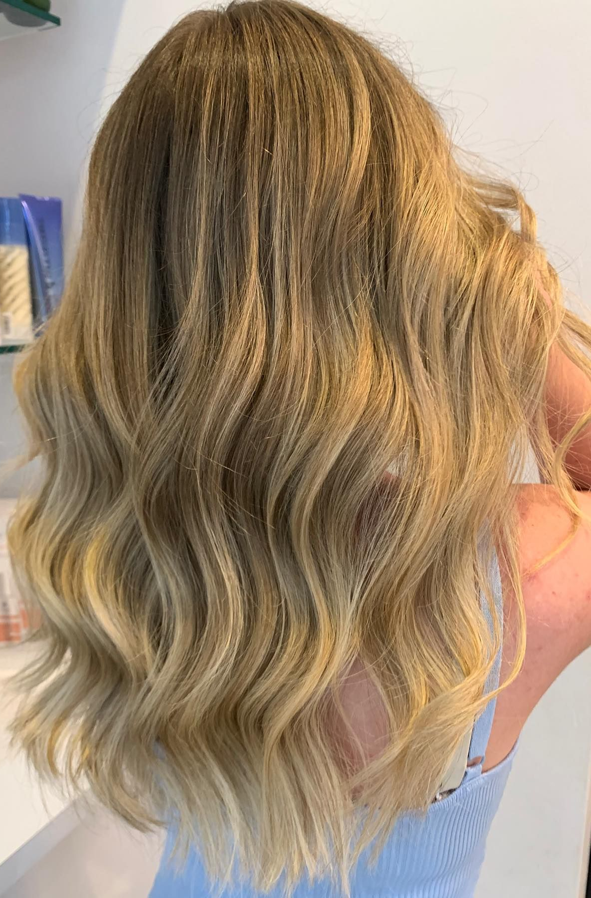 Woman With Long, Straight Blonde Hair in a Salon, Wearing a Black Cape — Artistry Of Hair in Redlynch, QLD
