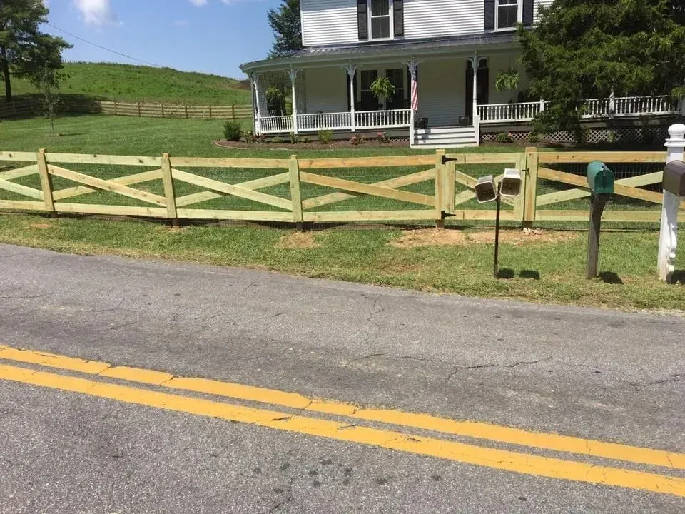 Rural farmhouse with white fence along a road on a sunny day.