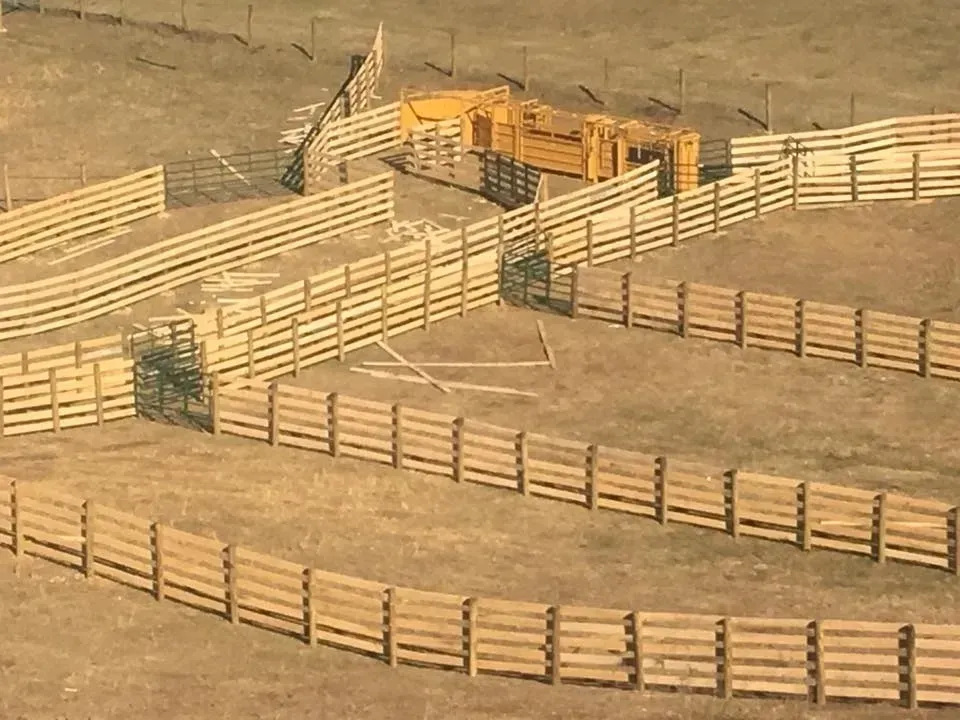 Wooden livestock corral with fenced pens and gates on a dusty hillside outdoors