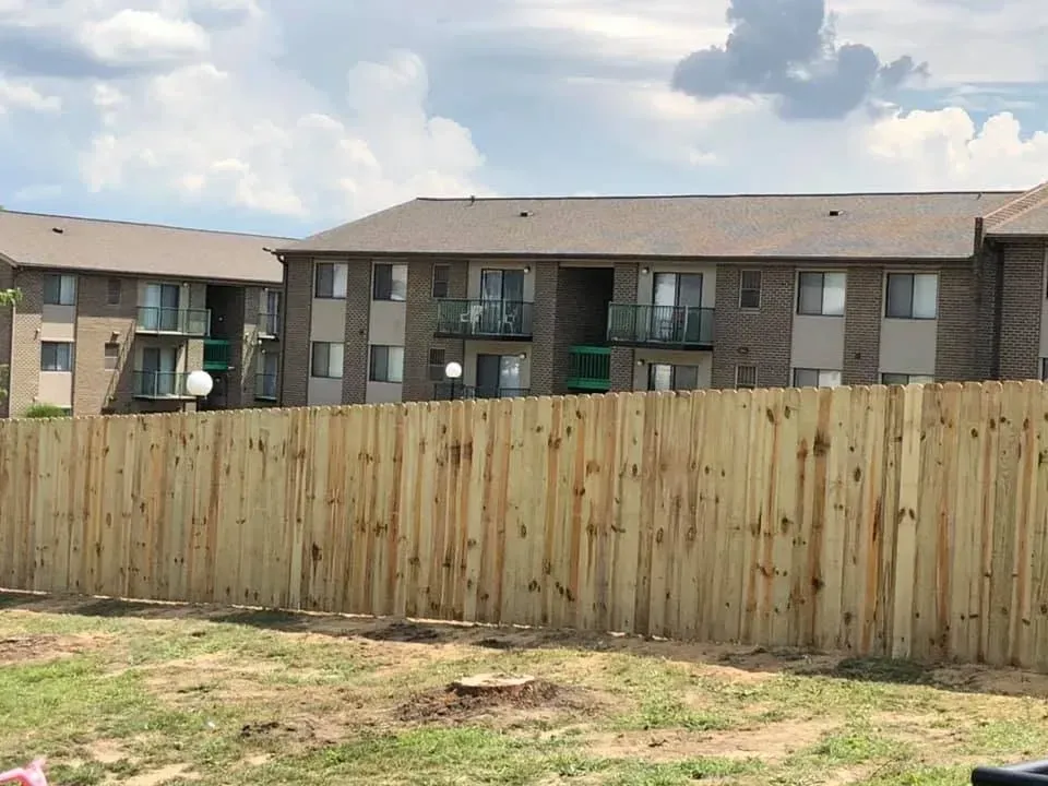 Wooden fence in front of apartment buildings under a partly cloudy sky