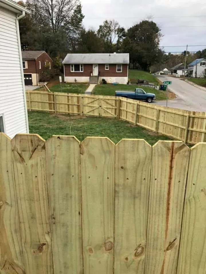 Wooden backyard fence with neighbor houses and a street visible beyond it