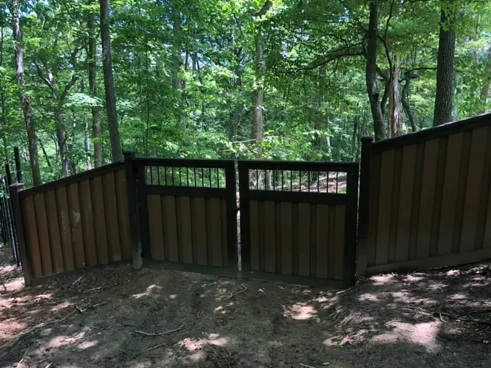 Brown wooden fence on a wooded trail with green trees in the background