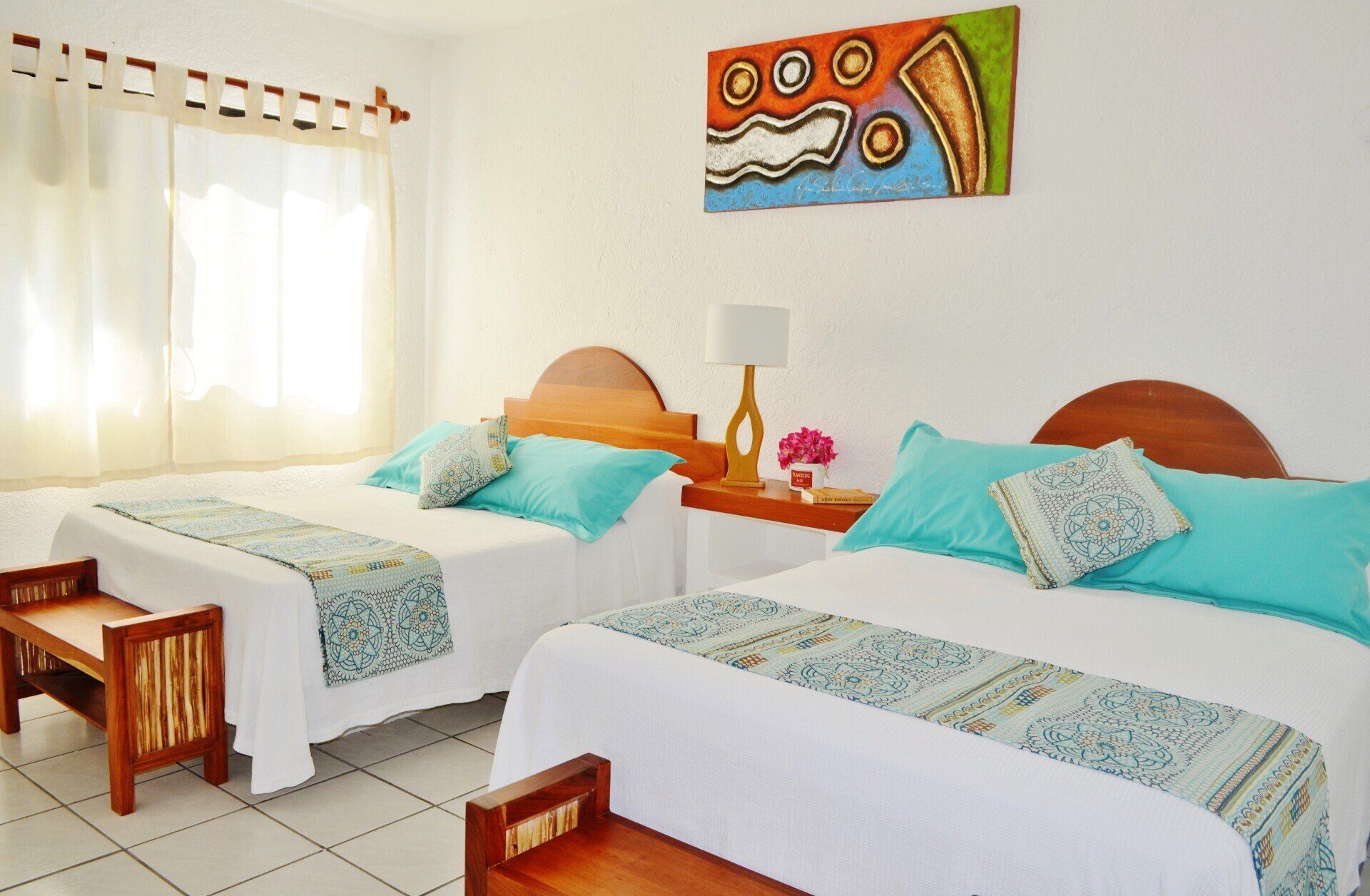 A hotel room with two beds and a painting on the wall