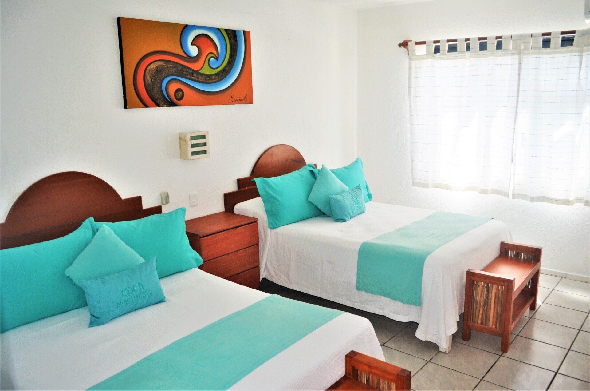 A hotel room with two beds and a painting on the wall.