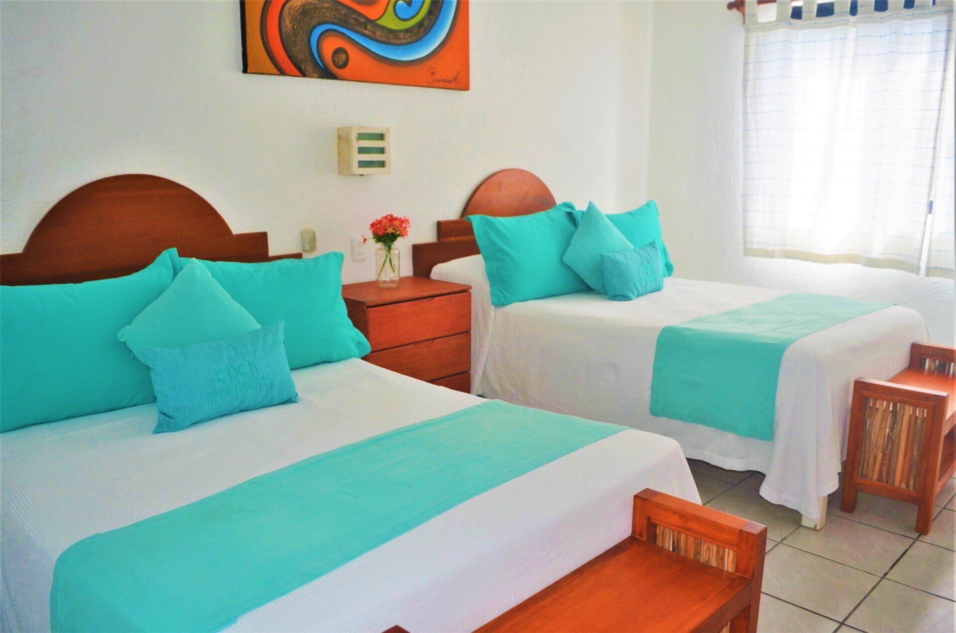 A hotel room with two beds and a bench.