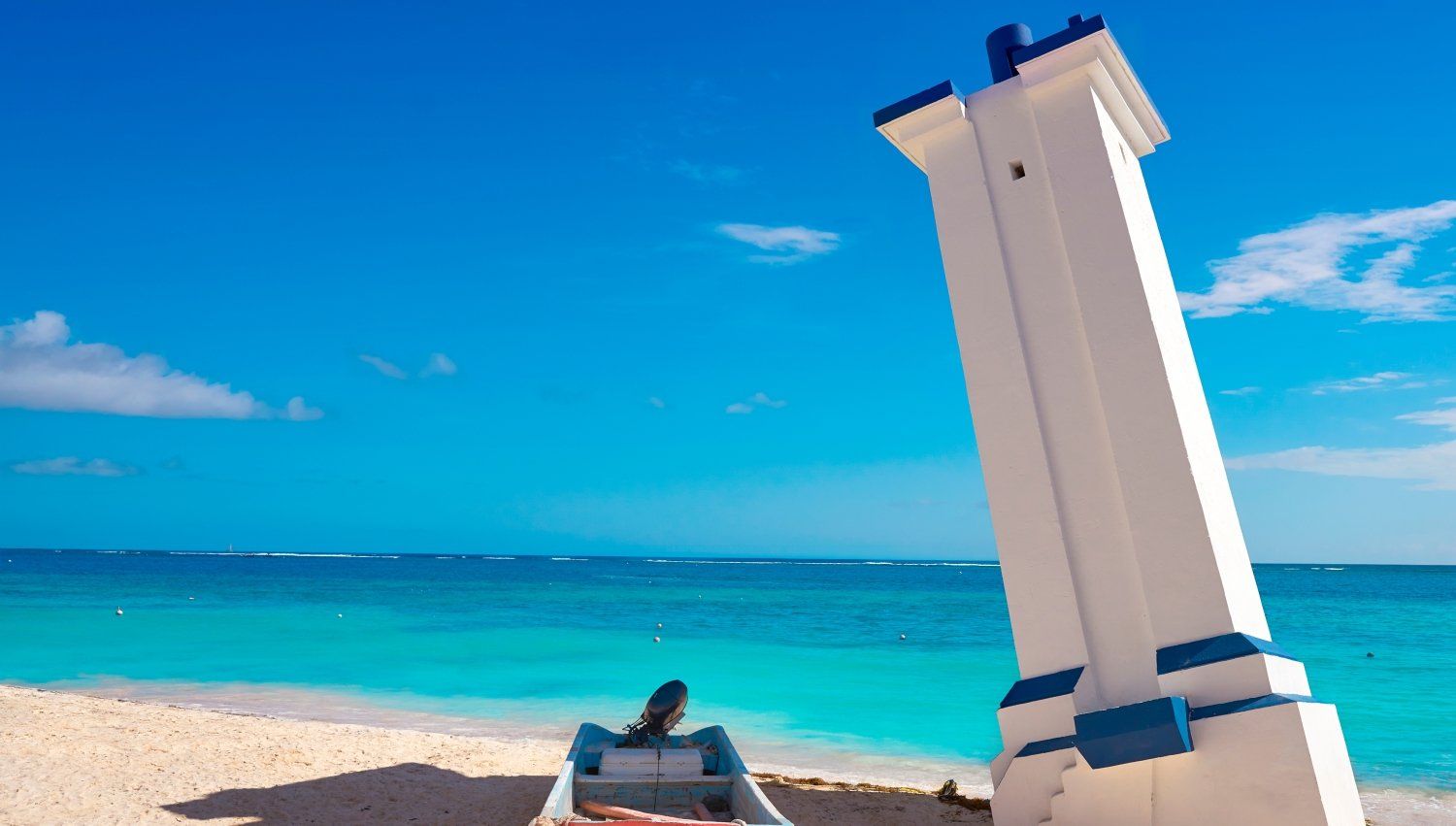 Un barco está sentado en la playa al lado de un faro.