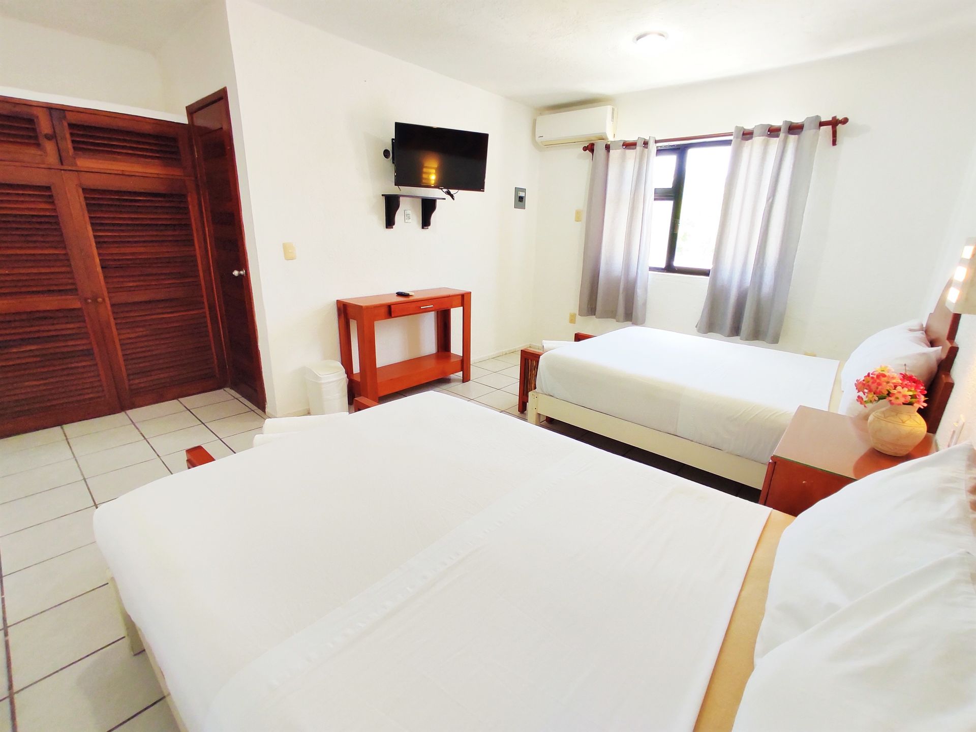 A hotel room with two beds and a television on the wall.