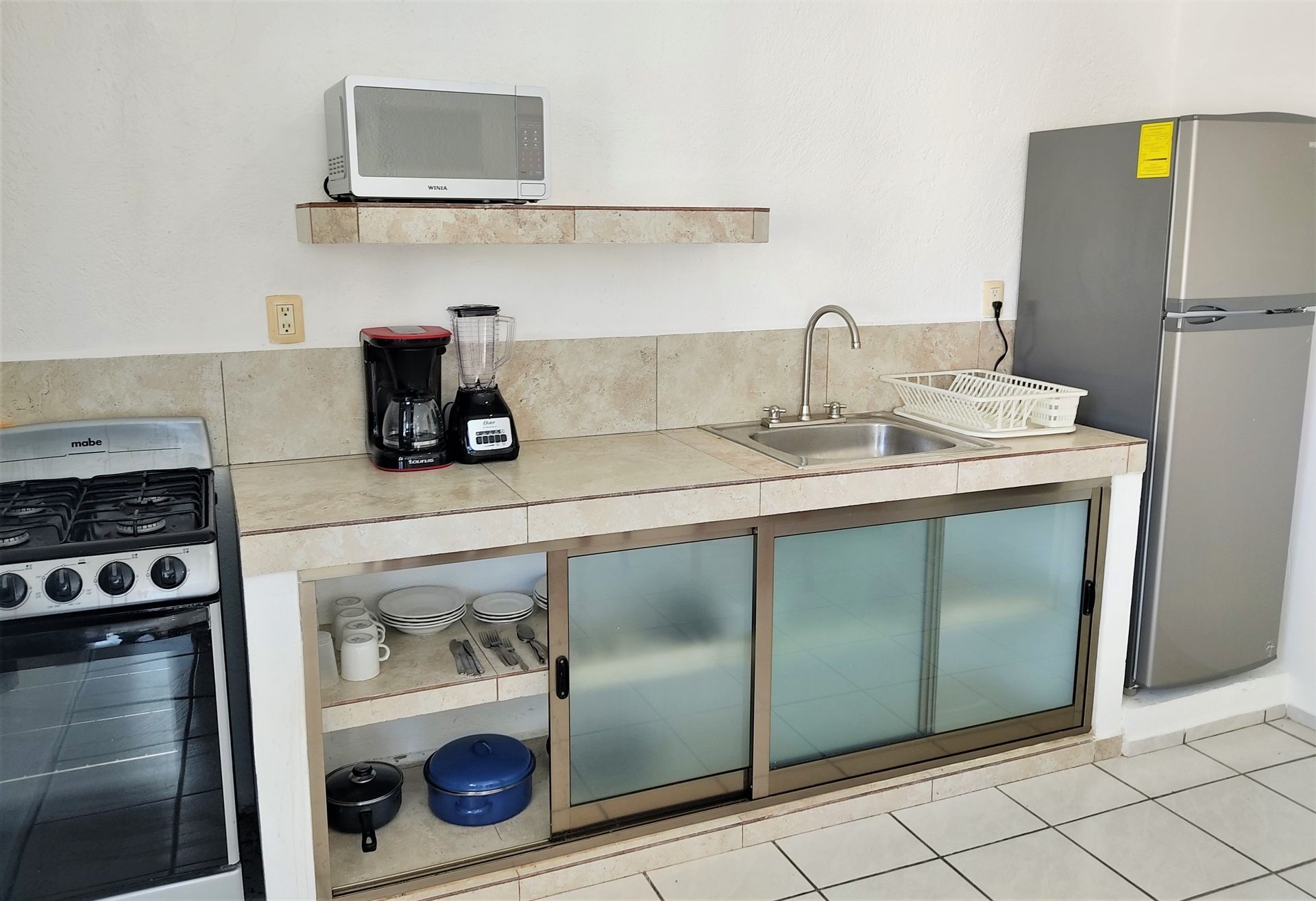 Una cocina con estufa, refrigerador, fregadero y microondas.