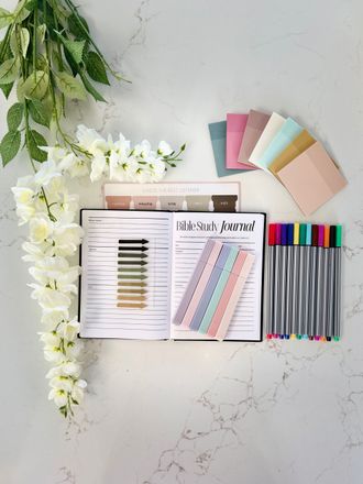 Colorful planner and notebooks arranged on a marble desk with flowers and pens