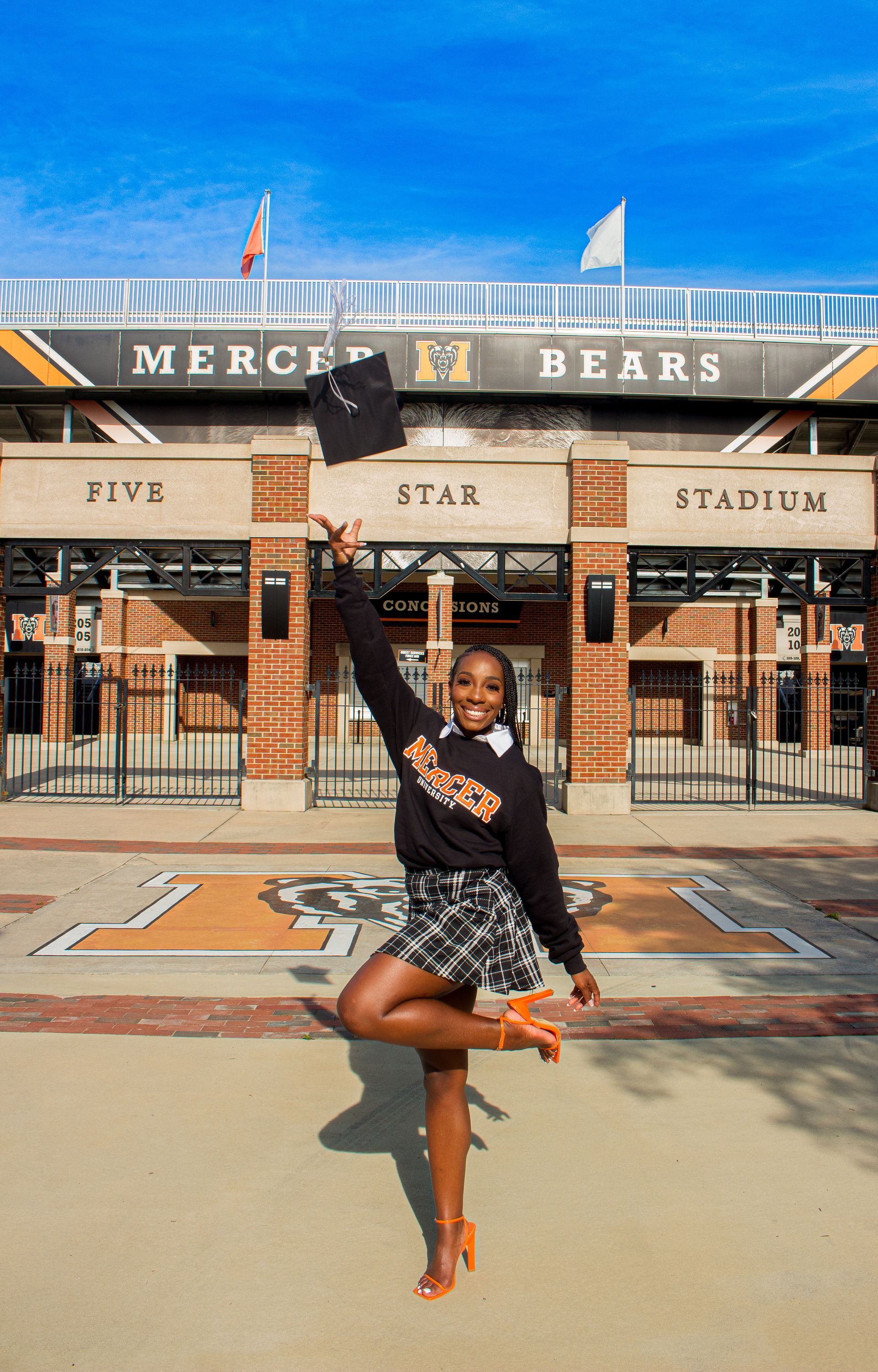 Person dancing in front of the “Mighty Bears” stadium entrance on a sunny day